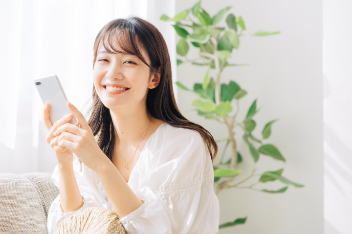 笑顔でスマホを持ってリラックスする女性