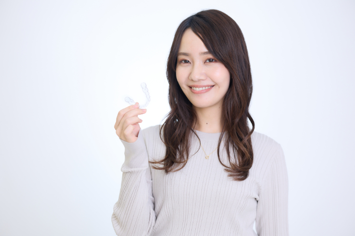 マウスピースを持って笑顔を見せる女性