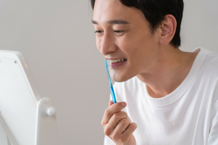 磨く箇所に合った当て方を意識して歯ブラシを縦に持って前歯を磨く男性