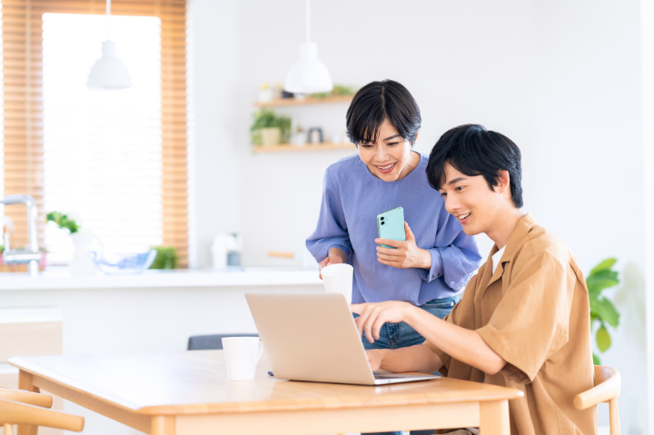 パソコンを見ながら会話する笑顔の夫婦